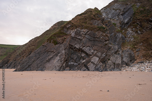 A rocky cliff with a sandy beach below