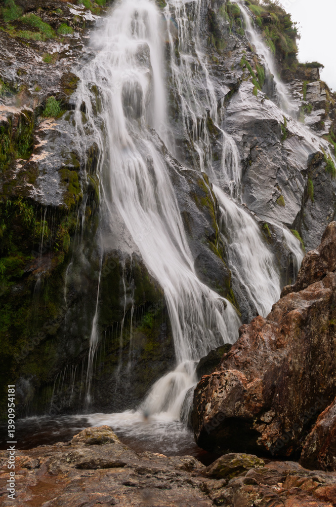 A waterfall is flowing down a rocky cliff A waterfall is flowing down a rocky cliff