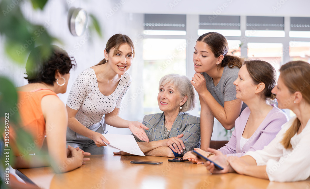 during teamwork, young female student holds paper documents in her hands and actively promotes her version of solution of educational task during teamwork, young female student holds paper documents in her hands and actively promotes her version of solution of educational task