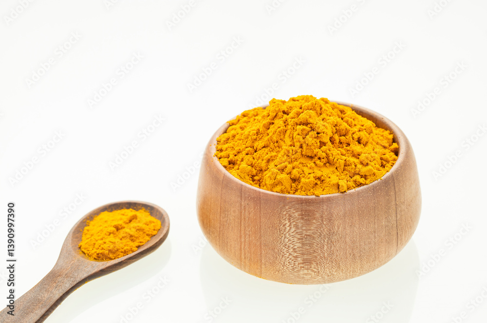 Finely dried turmeric powder in a bowl and wooden spoon - Curcuma longa Finely dried turmeric powder in a bowl and wooden spoon - Curcuma longa