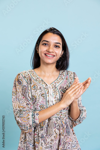 Indian satisfied woman clapping hands and feeling proud of a milestone in studio, pleased and satisfied with an achievement. Smiling adult applauding, saying congratulations for victory.