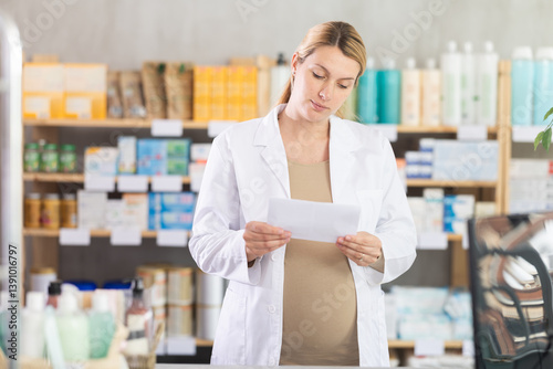 Obraz na płótnie Pregnant woman pharmacist checking medical prescription on computer in pharmacy w salonie