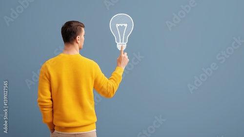 Obraz na płótnie Person in yellow sweater points at light bulb illustration on blue wall, symbolizing creative ideas and inspiration. w salonie