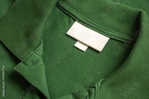 Blank white laundry care clothes label on green shirt fabric texture background