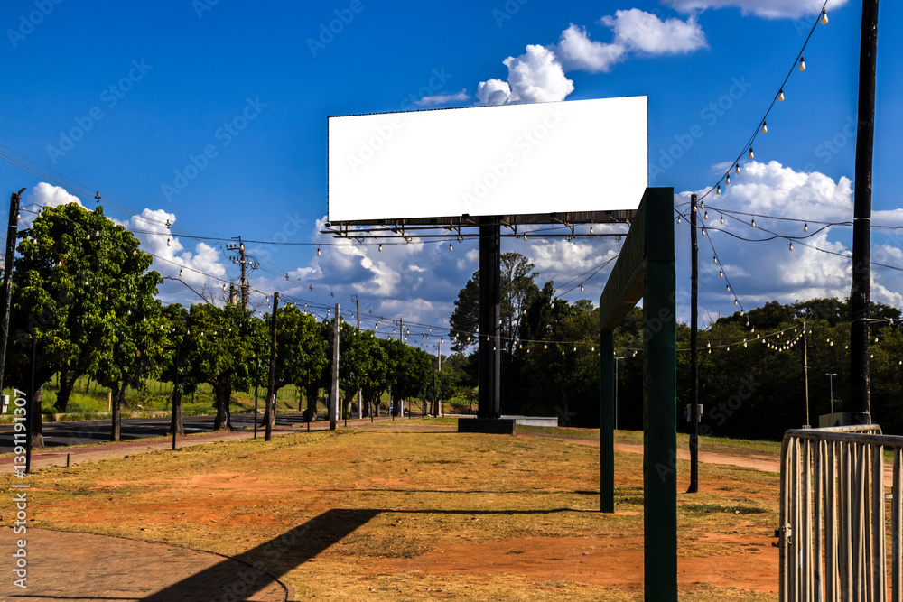 Mockup of the blank billboard under a bright blue sky with white clouds. Outdoor advertising space ready for a message. Simple and clean composition in Brazil
