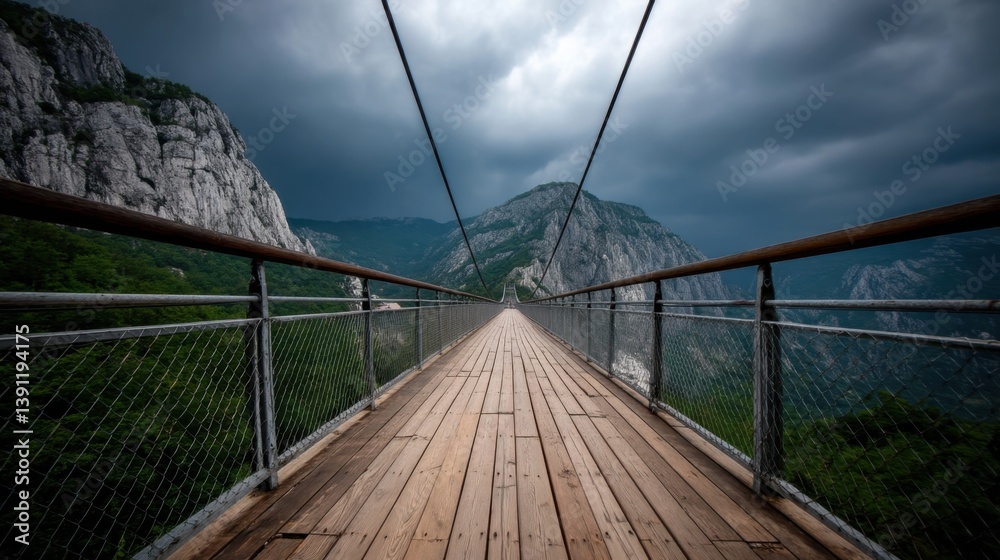 Obraz premium Suspension Bridge Between Mountains Under Cloudy Sky