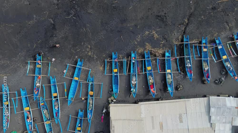 Top-down view of fishing boats docked on dark sandy beach on Depok Beach Yogyakarta