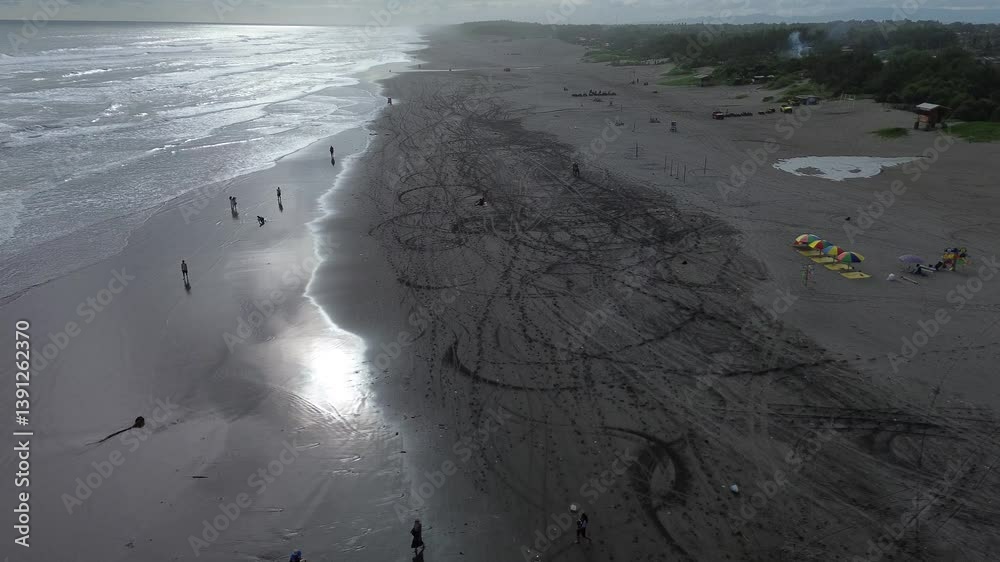 Parangtritis Beach scene with tourists enjoying activities on black sandy beach with scenic ocean view