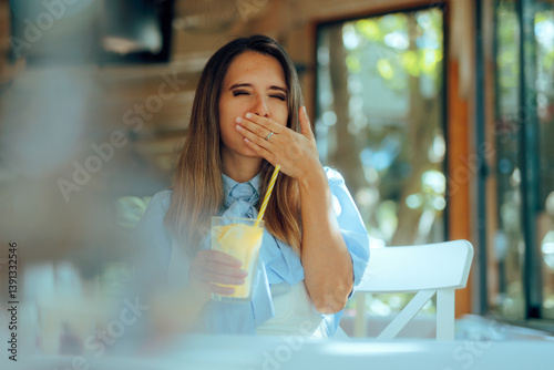 Woman Drinks Lemonade and Covers Her Mouth in a Restaurant. Lady belching feeling uncomfortable from beverage acidity
