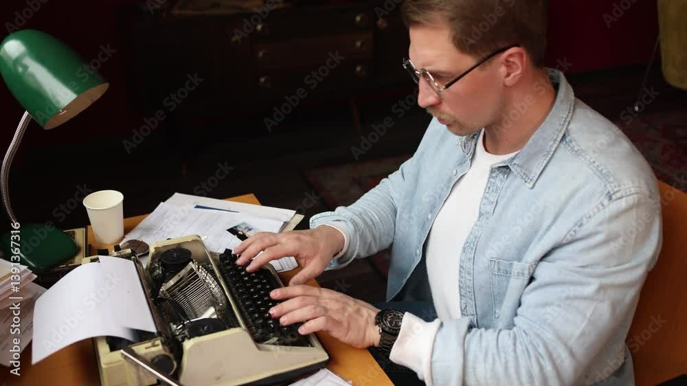 Writer in creative thought at vintage typewriter, cinematic soft-focus on smoky paper-strewn office scene.