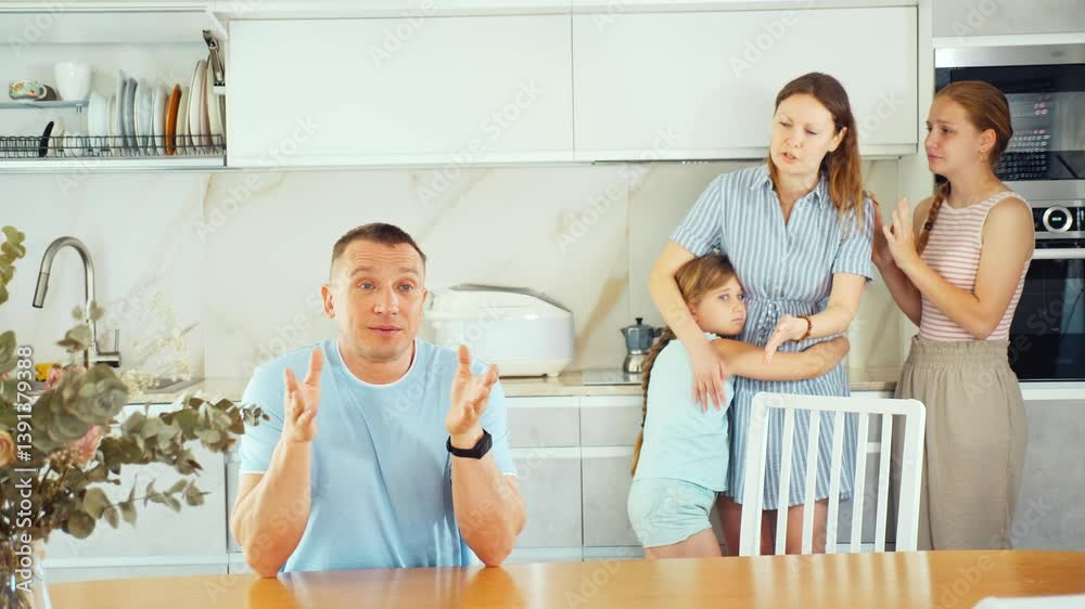 Thoughtful father is sitting in kitchen and thinking about ways to solve difficult financial situation. Wife with children stand behind dad and are afraid to ask about current problem Thoughtful father is sitting in kitchen and thinking about ways to solve difficult financial situation. Wife with children stand behind dad and are afraid to ask about current problem