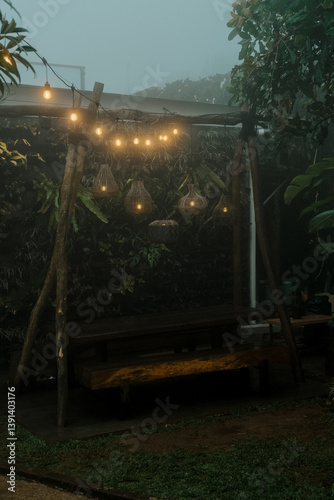Wooden bench and hanging lanterns in a foggy forest. Suitable for naturethemed designs, outdoor event promotions, serene backgrounds, and relaxation concepts. photo