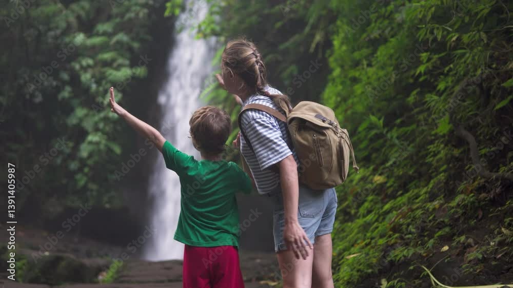Woman and little boy are enjoying view of awesome waterfall