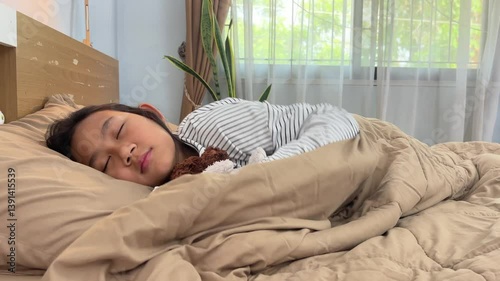 Asian young cute girl sleeping under a blanket on the bed