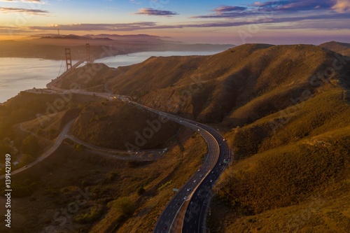 Golden Gate Bridge view from the Marin Headlands at sunrise. Cars travel on Highway 101, connecting San Francisco, California, USA.