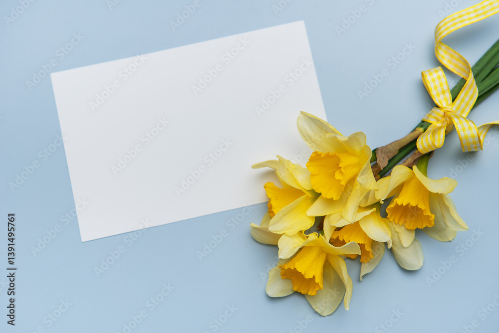 Bouquet of daffodils with greeting card lying on blue table