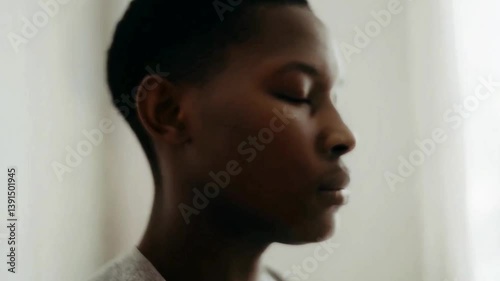 Black person with eyes closed practicing mindfulness in a calm indoor space, focused on meditation or mindful breathing, reflecting peace, balance, and emotional self-awareness

