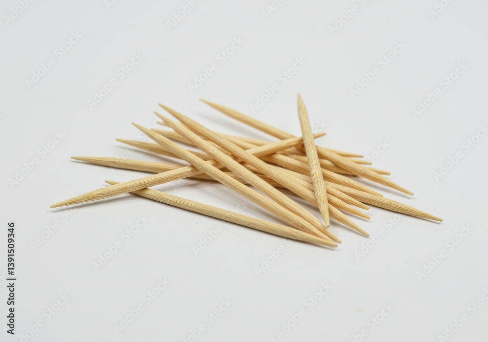 A group of wooden toothpicks scattered on a white surface in a close up studio shot view from above A group of wooden toothpicks scattered on a white surface in a close up studio shot view from above