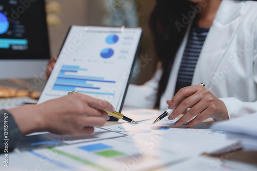 Foto Two businesswomen collaborating on a project, analyzing financial charts and gra