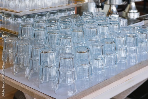 Row of identical clean transparent water glasses stacked in row on a table, served for event