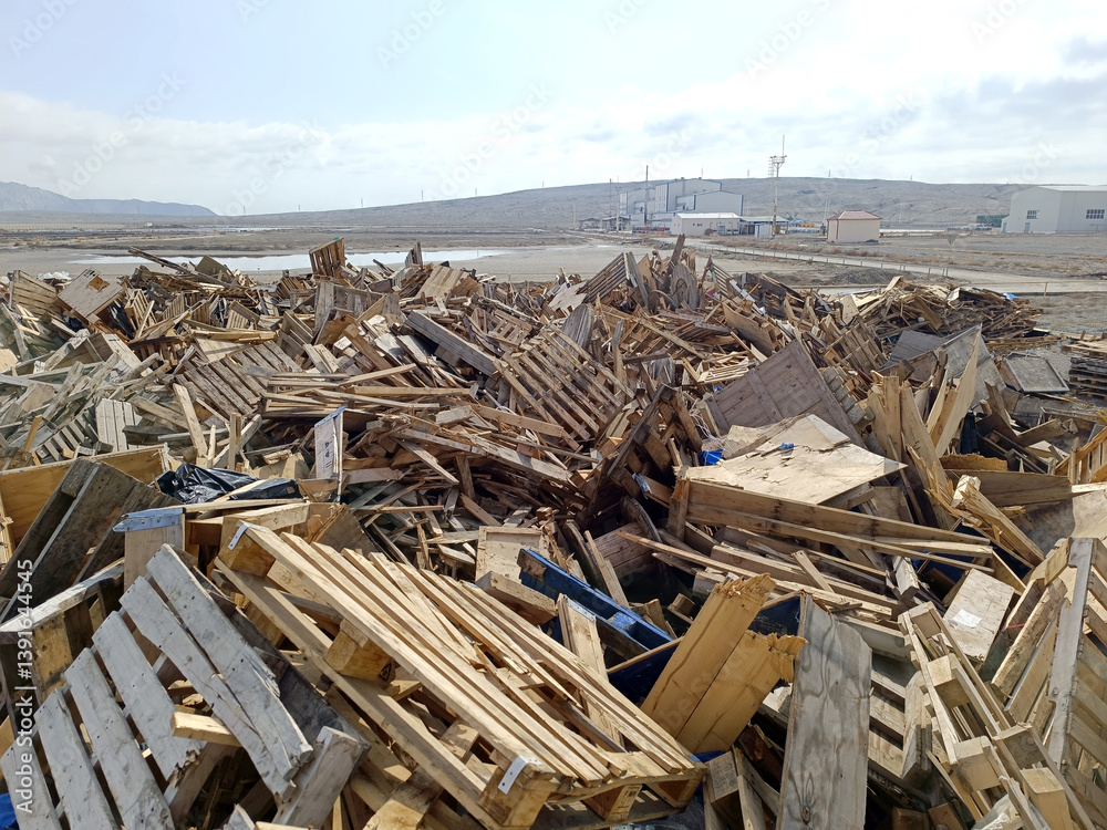 Wood waste collected for recycling outdoors in the Waste Center area. Mixed wood waste. Iron structure warehouse and mountains in the background of wood waste Wood waste collected for recycling outdoors in the Waste Center area. Mixed wood waste. Iron structure warehouse and mountains in the background of wood waste