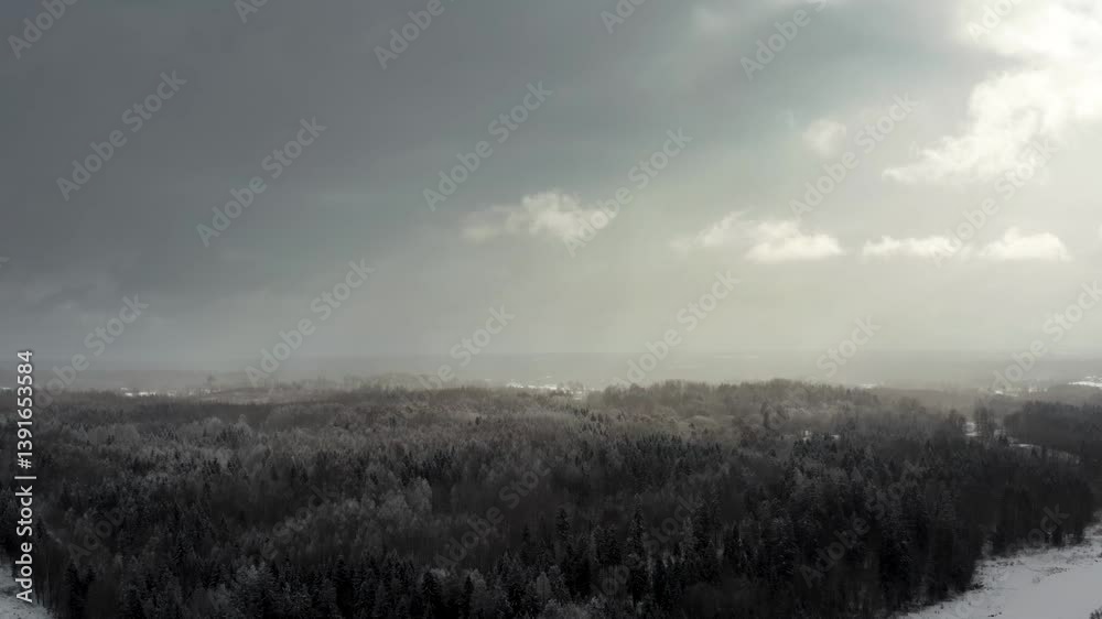 Aerial view of dramatic sky over the forest with sun rays breaking through the clouds over a forest in winter landscape. Aerial view of dramatic sky over the forest with sun rays breaking through the clouds over a forest in winter landscape.