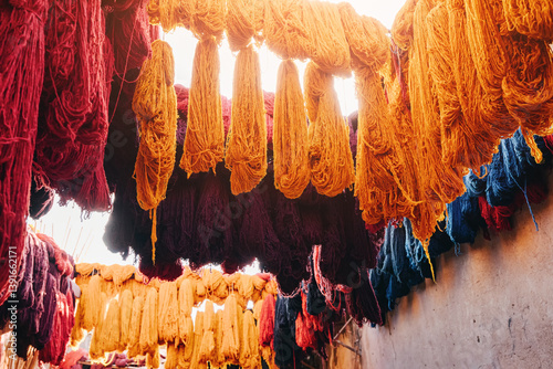 Obraz na płótnie Skeins of vibrant, colorful wool yarn hanging and drying in a traditional Moroccan tannery, showcasing the artistry of local craftsmanship w salonie