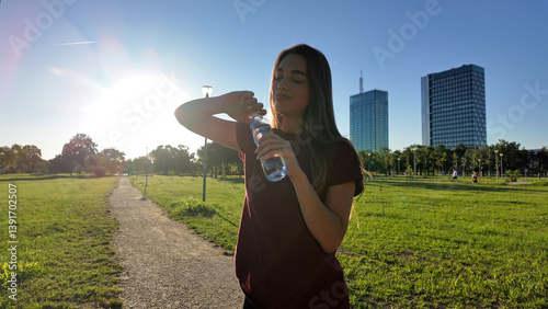 Obraz na płótnie Young exhausted woman drinking water after jogging and exercise in urban park. w salonie