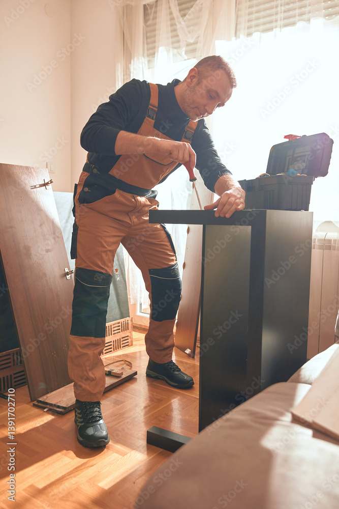 Carpenter working and assembling furniture in a new apartment.