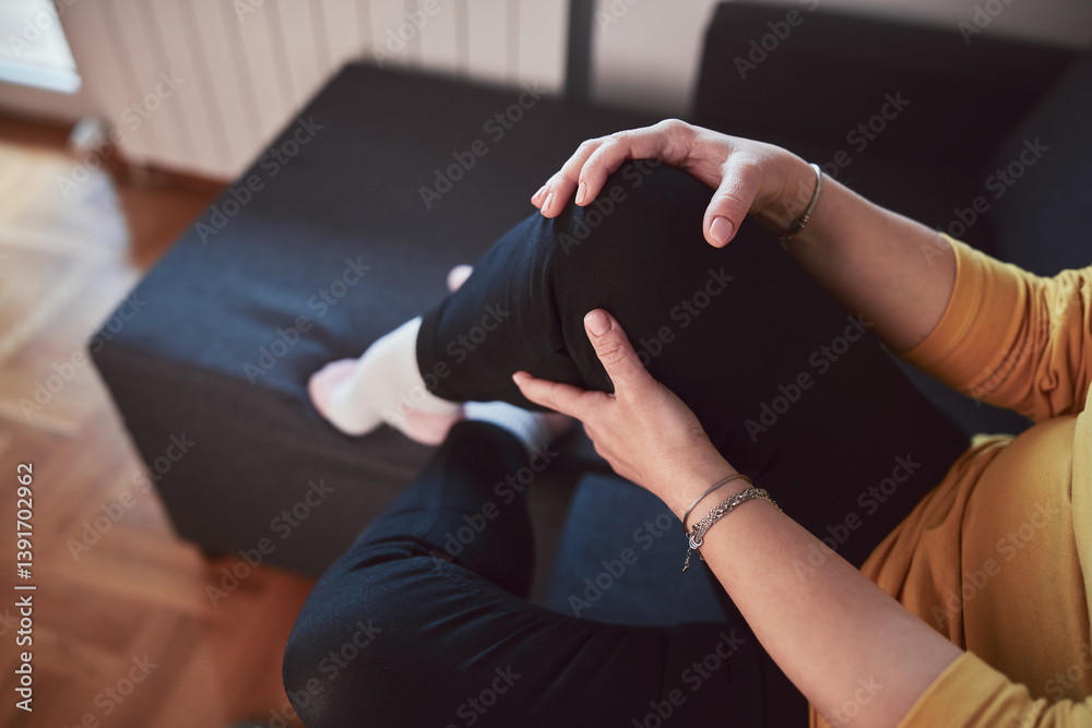 Woman with painful knee and leg injury at home.