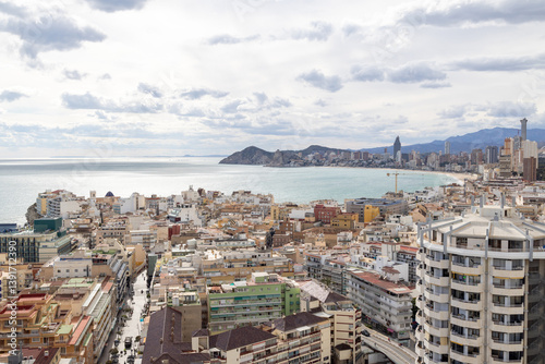 Obraz na płótnie Aerial photo of the Spanish town of Benidorm in Spain showing the old town of the city with the beach known as Platja de Ponent or West Beach Promenade in background as well as mountains and clouds w salonie