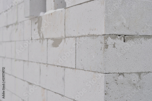 Close-up of a wall made from white aerated concrete blocks. The surface shows texture, seams, and mortar. Part of an unfinished construction under cold weather conditions.
