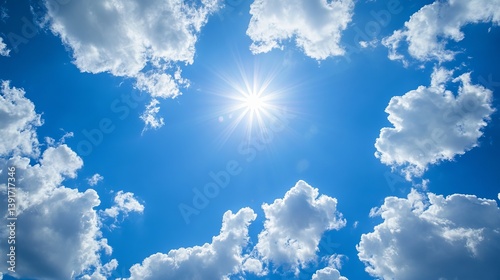 Fototapeta Naklejka Na Ścianę i Meble -  A bright sun shining in a blue sky with fluffy white clouds scattered around the sun and sky above