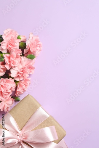 Happy Mother's Day. Beautiful bouquet of pink carnations with gift box on a colored background