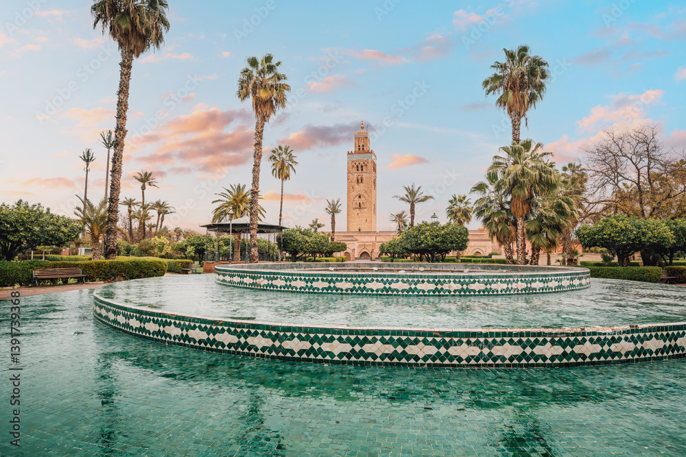 The majestic Koutoubia Mosque rises above a serene fountain in Marrakech, Morocco, bathed in the warm glow of the setting sun
