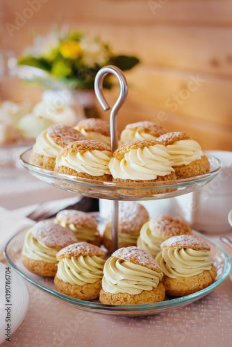 Two-tier stand filled with elegant choux pastry desserts, each topped with smooth, neatly piped cream. Perfect for wedding dessert tables, buffet catering, afternoon tea parties, or festive celebratio