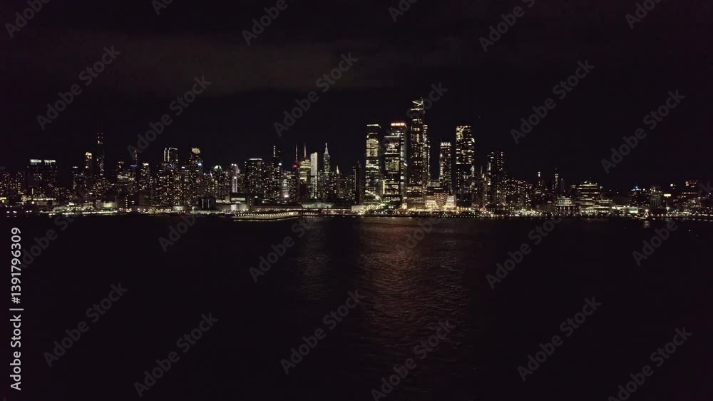 Serene nighttime view of New York City’s skyline seen across calm Hudson River waters, with buildings glowing and reflecting under a dark sky. Serene nighttime view of New York City’s skyline seen across calm Hudson River waters, with buildings glowing and reflecting under a dark sky.