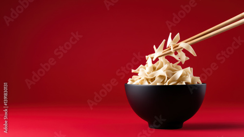 Light Beige Noodles in Black Bowl with Chopsticks on Red Background