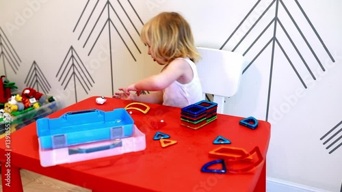 Child enjoys creative play with colorful stacking shapes at indoor play area
