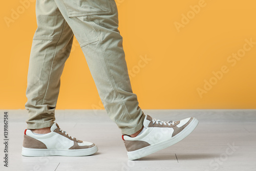 Obraz na płótnie Young man in stylish sneakers near yellow wall, closeup w salonie