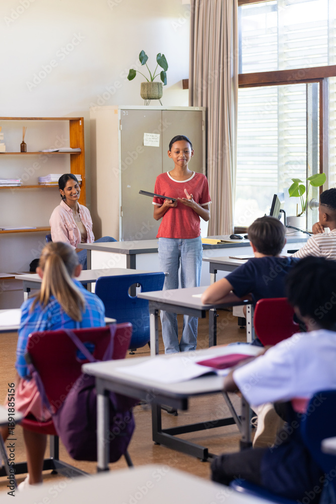 Obraz premium Holding book, woman teaching in classroom with students listening attentively in school