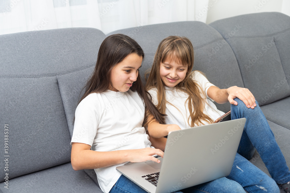 Cute little girl and older sister playing together smiling and having bonding time using a laptop on couch at home. Happy family Siblings relationship and digital technology lifestyle concept. Cute little girl and older sister playing together smiling and having bonding time using a laptop on couch at home. Happy family Siblings relationship and digital technology lifestyle concept.
