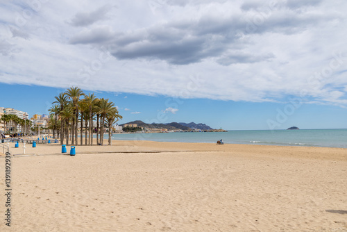 Obraz na płótnie Photo of the beautiful town of Villajoyosa in Spain showing the lovely sandy beaches on a hot sunny day with palm trees on the beach w salonie