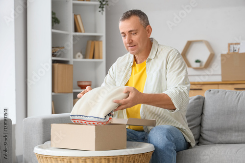 Obraz na płótnie Mature man unpacking box with sweater at home w salonie