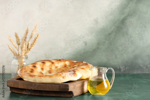 Obraz na płótnie Wooden tray with tasty lavash and jug of oil on green grunge table w salonie