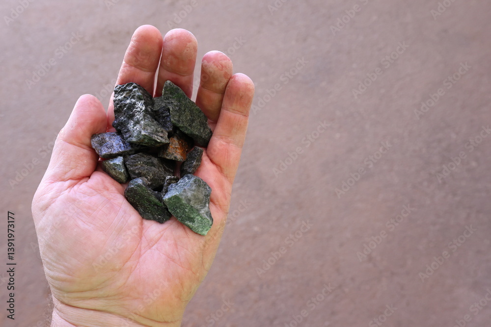 Scheelite ore held in hand. Mined for tungsten (wolfram), used to produce tungsten carbide, alloys and steels, hard permanent magnets, ammunition designed to penetrate vehicle armor in war Scheelite ore held in hand. Mined for tungsten (wolfram), used to produce tungsten carbide, alloys and steels, hard permanent magnets, ammunition designed to penetrate vehicle armor in war