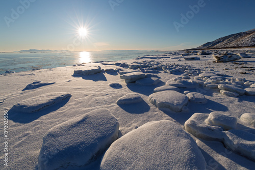 Obraz na płótnie Winter seascape. View of ice floes on the seashore. Snow-covered ice. In the distance, unfrozen sea. Bright sunlight. Cold weather. Coast of the Sea of Okhotsk, Magadan region, Far East of Russia. w salonie