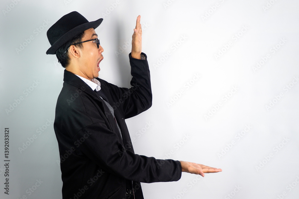 Asian man dressed as a mafia wearing glasses and a hat, pointing to the side with a surprised expression Asian man dressed as a mafia wearing glasses and a hat, pointing to the side with a surprised expression
