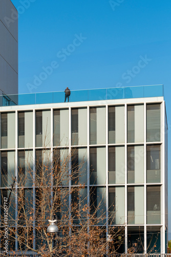 Facade of modern business building in Barcelona with bare trees and bright sky in residential financial zone