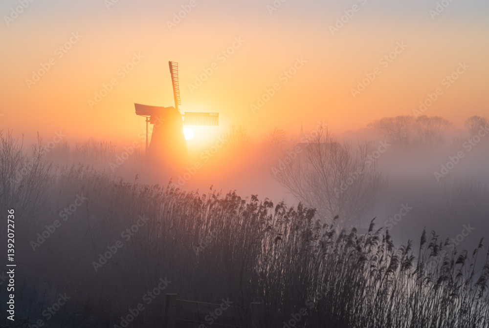 Dawn at a traditional, Dutch windmill in the spring fog.